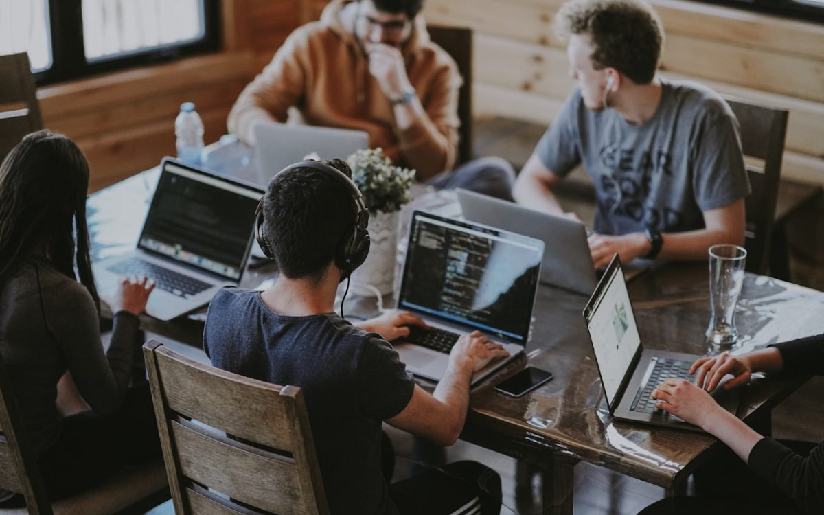 A small team working together around a table of laptops